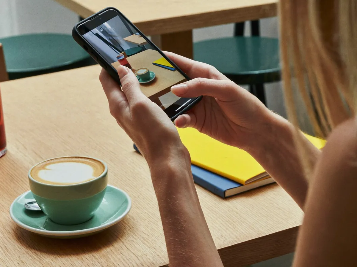 Hands holding a phone over a cafe table